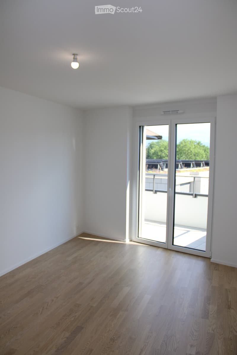 Empty room with wooden flooring, white walls, and a large sliding glass door leading to a balcony.