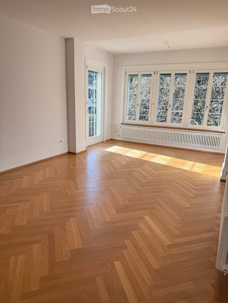 Empty room with parquet flooring, white walls, glass doors, large windows, and built-in radiators