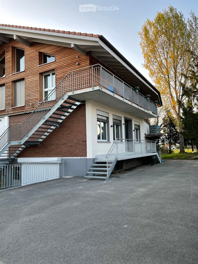Two-story house with brick and wooden exterior, multiple balconies, and stairs leading to the upper level.