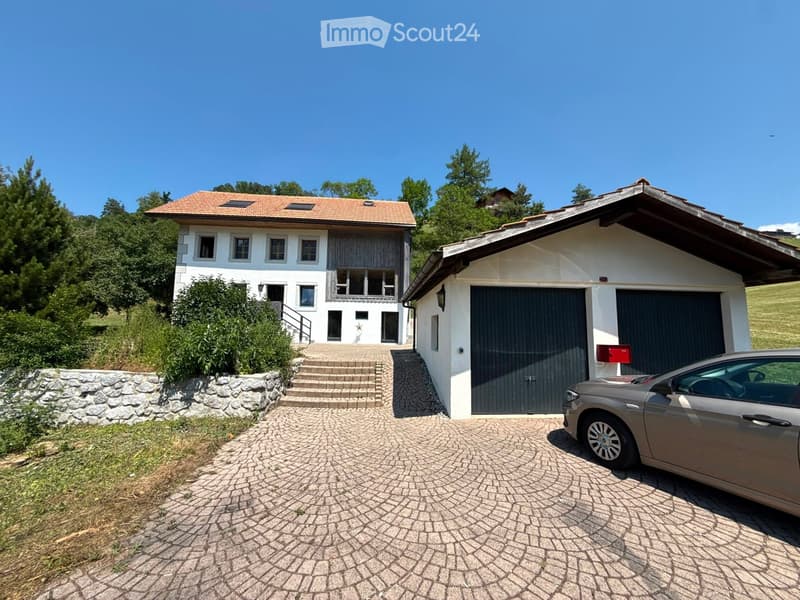 Two-story house with a garage, stone steps leading to the entrance, and a parked car in front.