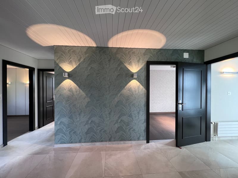 Modern hallway with patterned wallpaper, recessed lighting, and multiple doors leading to other rooms.
