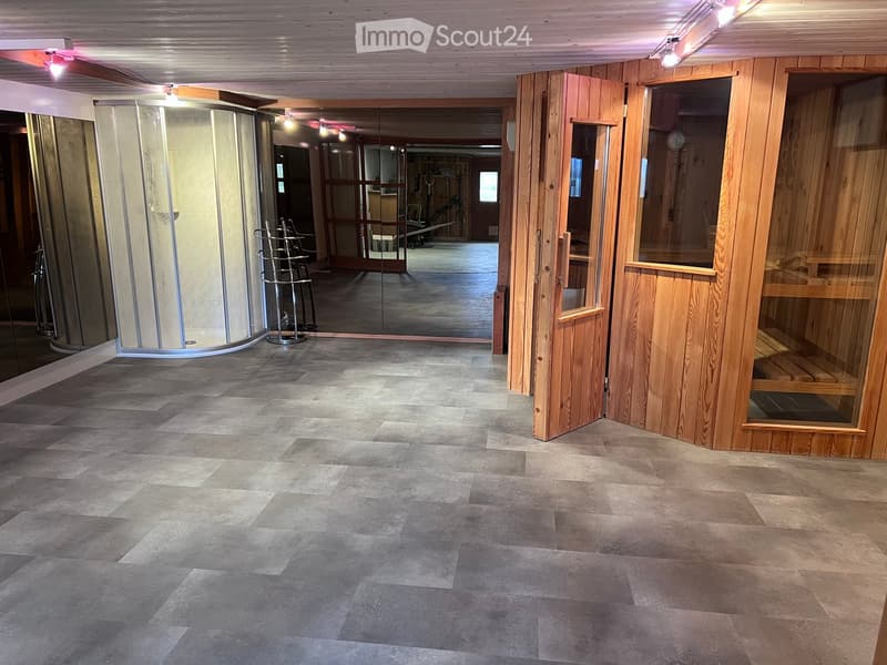 Spacious hallway with wooden paneling, tiled floor, glass shower enclosure, and wooden doors leading to other rooms.