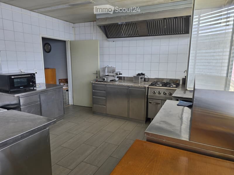 Commercial kitchen with stainless steel appliances, granite countertops, and tiled walls.