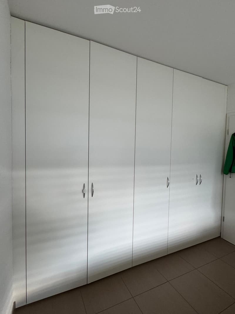 Empty room with white built-in wardrobes and tiled floor.