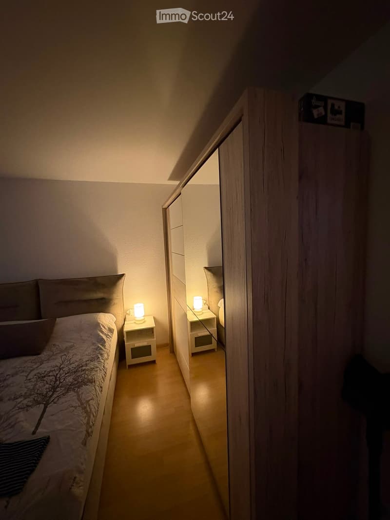 Cozy bedroom with a double bed, nightstands, lamps, and a wardrobe. The room features warm lighting and a modern design.