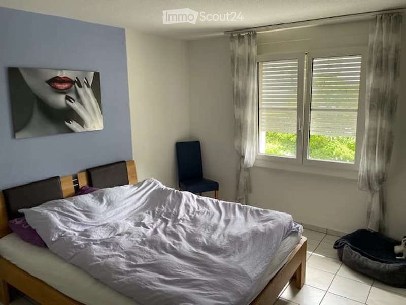 bedroom with bed, chair, window with curtains, painting on wall, dog bed
