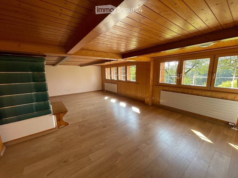 Empty room with wooden floors and wooden walls, large windows, and radiators. No furniture or equipment present.