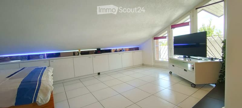 Bright, modern room with white tiled flooring, a large window with blinds, a bed with blue and white bedding, a white cabinet with drawers, and a TV on a stand.
