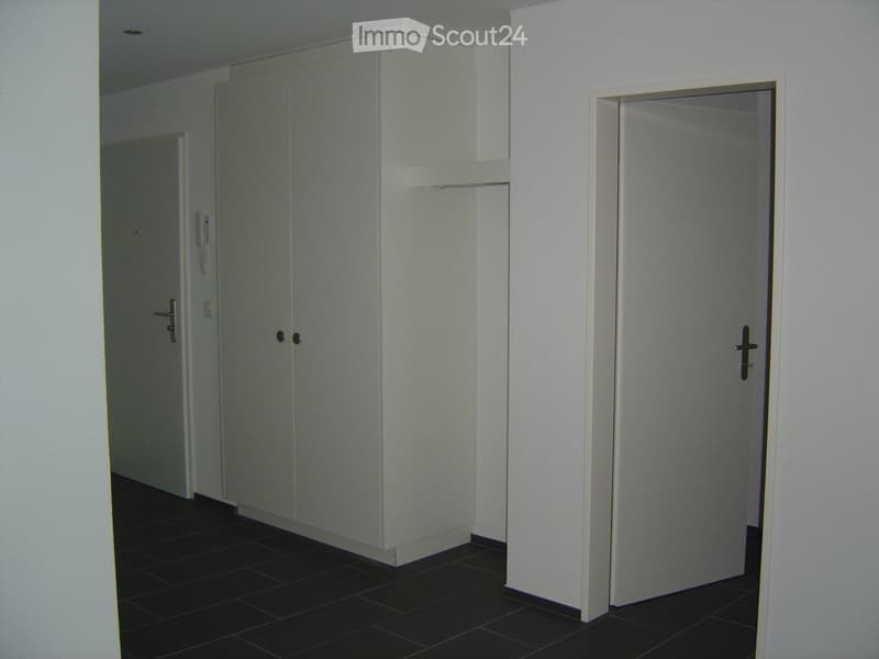 Empty hallway with white walls, dark tiled floor, and two closed doors.