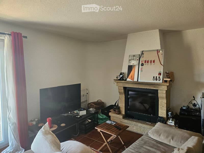 Living room with a fireplace, sofa, coffee table, television, and a small wooden table.