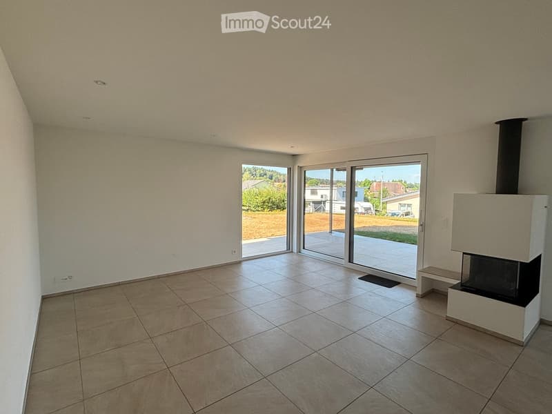 Empty room with tiled floor, white walls, large sliding glass doors leading to a patio, and a modern fireplace with a chimney.
