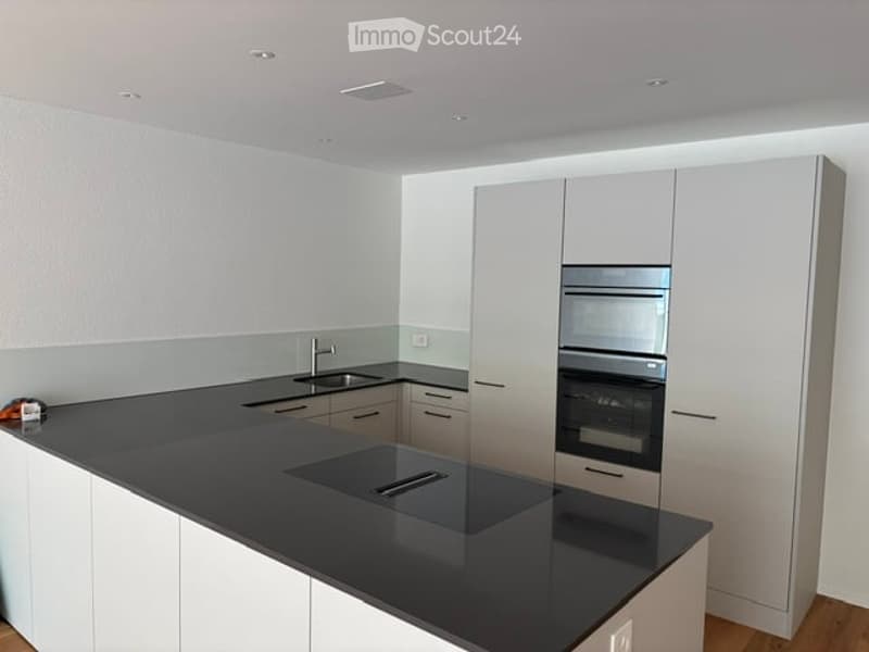 Modern kitchen with white cabinets, black countertop, island, sink, and built-in oven and microwave.