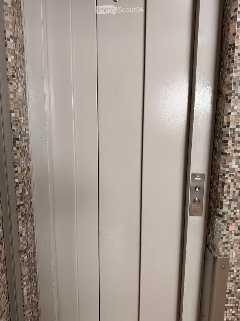 Elevator doors with mosaic tile accents and an Otis brand control panel visible.