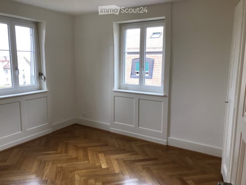 empty room, wooden parquet floor, white walls, two windows, white window frames, power outlet