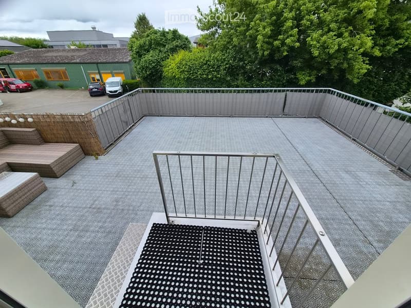 Roof terrace with modern metal railing, grey flooring, and a wooden seating area with steps.