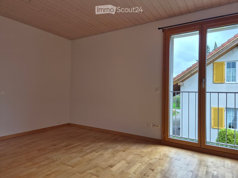 Empty room with wooden flooring, light-colored walls, and a large sliding glass door leading to a balcony.