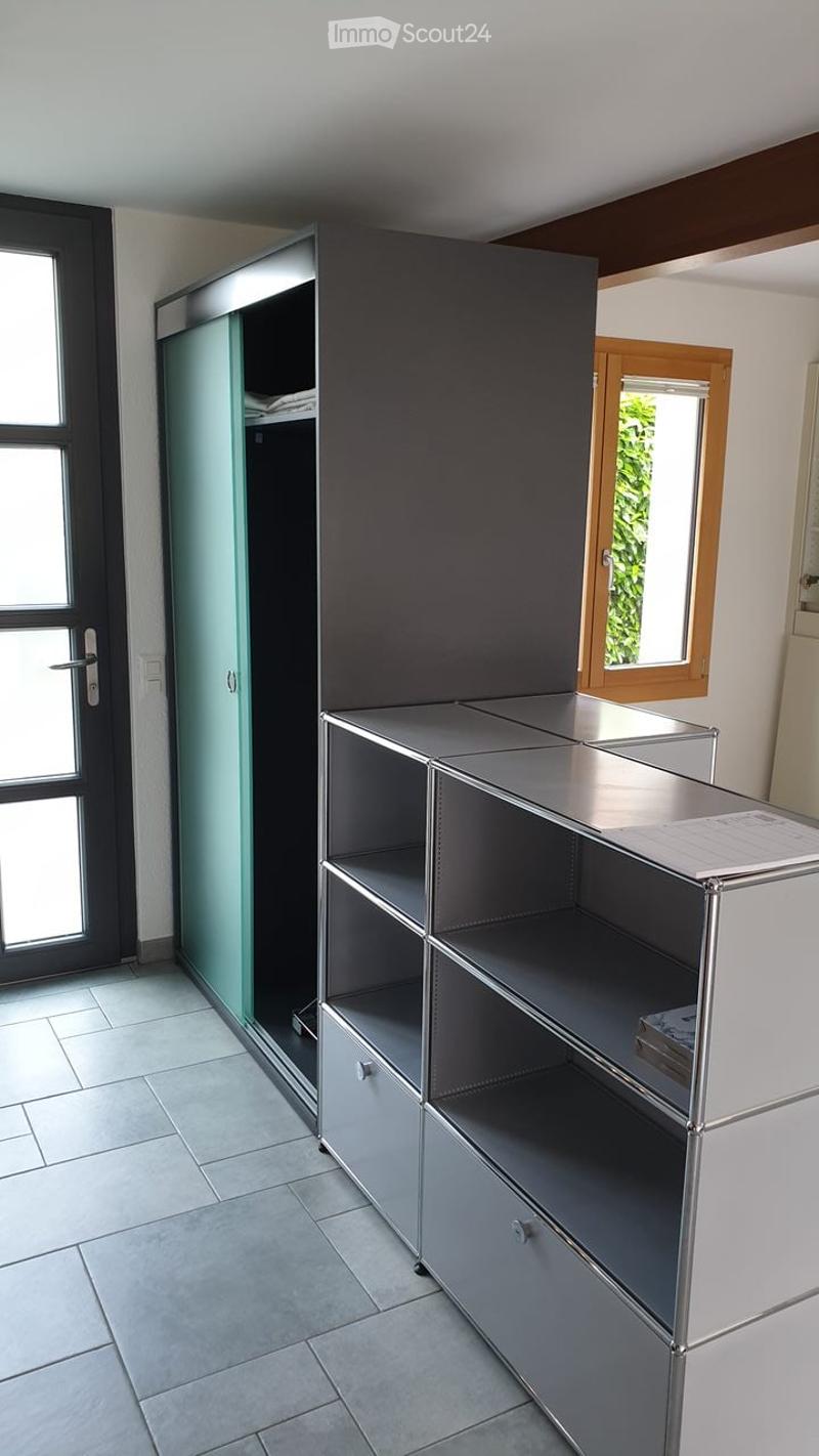 Empty room with tiled floor, grey cabinet, and a glass door leading outside.