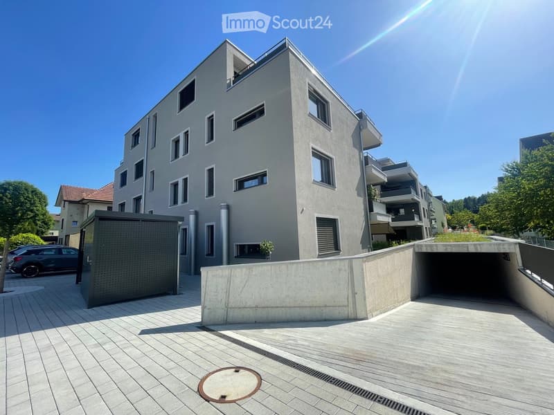 4 story modern apartment building, gray exterior, balcony, underground parking entrance, covered passageway