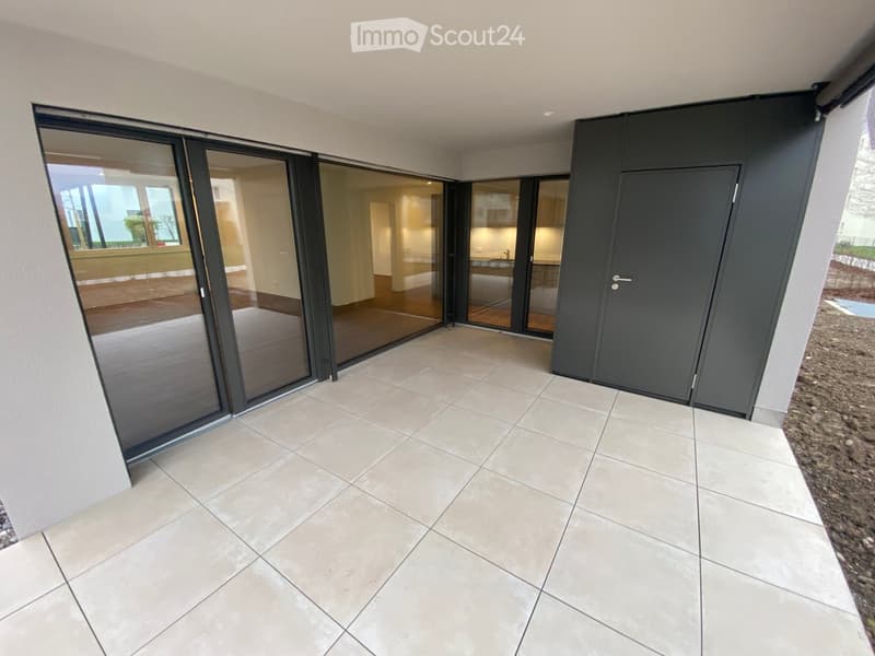 Modern balcony with large sliding glass doors, tiled floor, and a view into the interior of the house.
