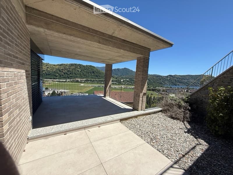 Spacious balcony with tiled flooring, wooden ceiling, brick columns, and a scenic mountain view.