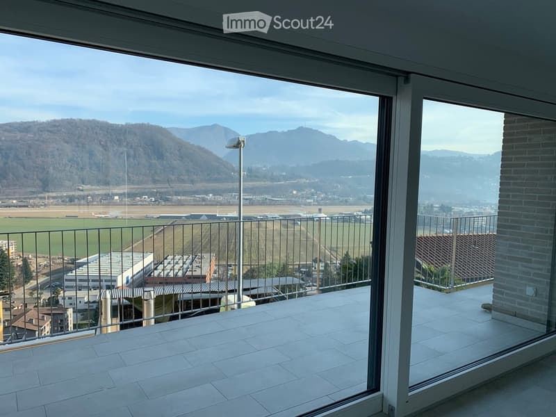 Balcony with large glass doors, tiled floor, metal railing, and scenic mountain view.