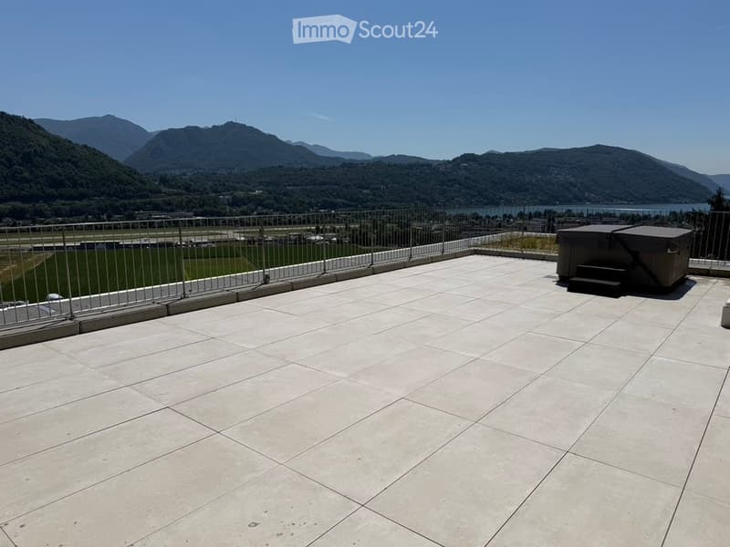 Roof terrace with tiled flooring, metal safety railing, and scenic mountain and lake view.
