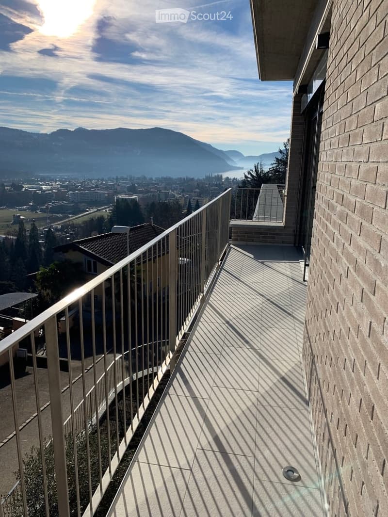 Balcony with metal railing, tiled floor, and scenic view of mountains and cityscape.
