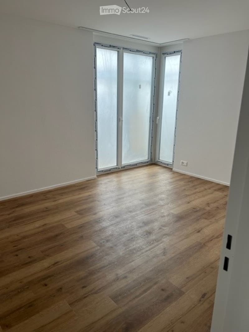 Empty room with wooden flooring and large glass sliding doors leading to a balcony.