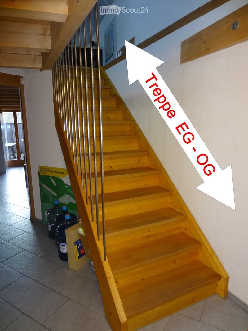 Wooden staircase with metal railing, leading to upper floor, with arrows indicating directions to ground floor (EG) and upper floor (OG).