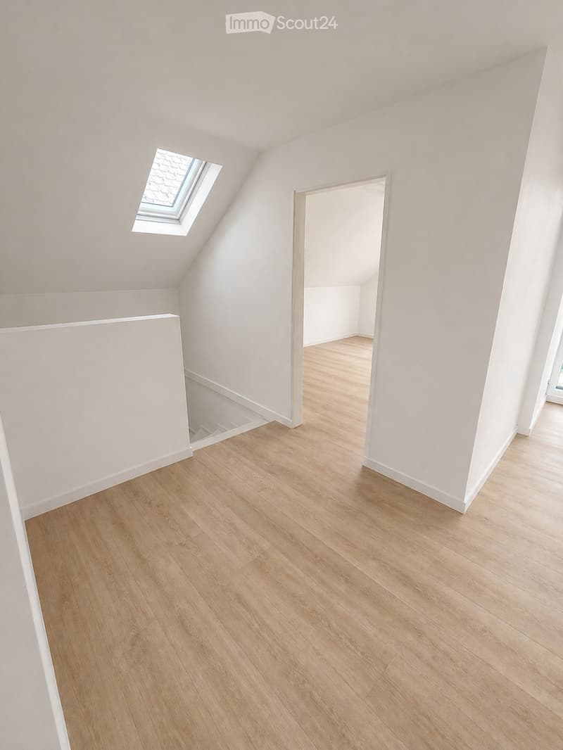 Empty attic room with wooden flooring, white walls, and a skylight window. No furniture or equipment present.
