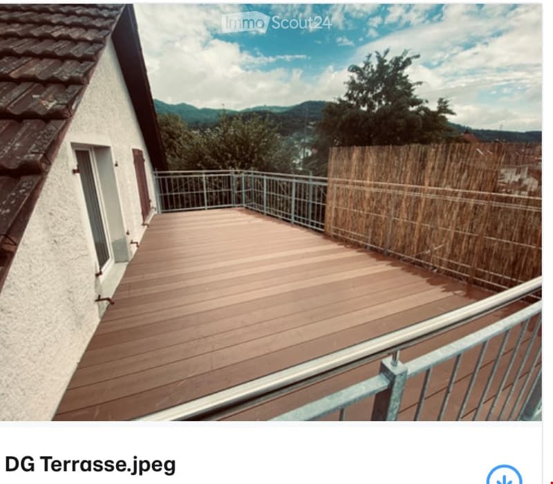 Wooden deck terrace with metal railing, bamboo screen, and scenic mountain view.