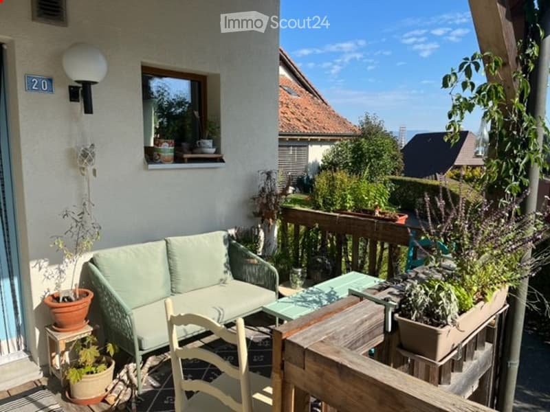 Balcony with a small couch, wooden chair, green table, and potted plants