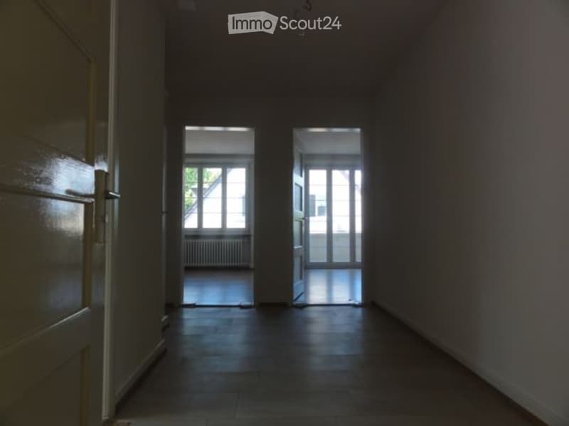 Empty hallway with wooden flooring, white walls, and two open doorways leading to other rooms.