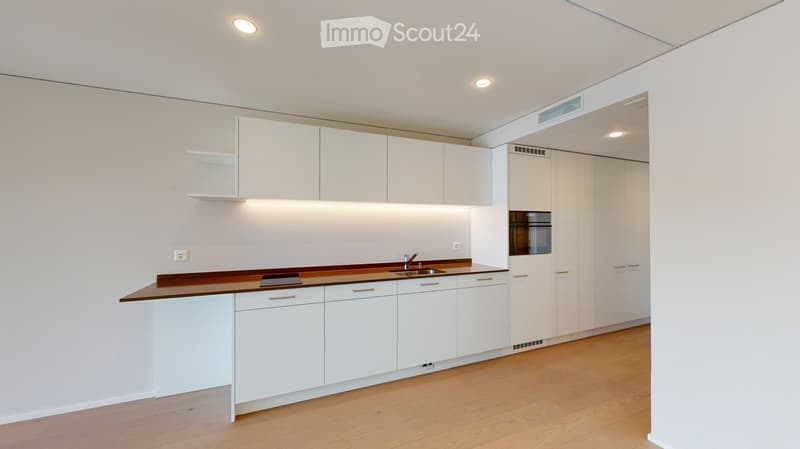 Modern kitchen with white cabinets, wooden countertops, and built-in appliances.