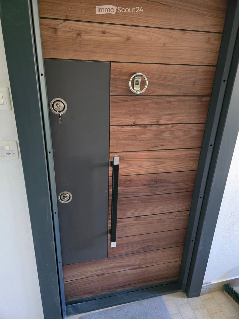 Modern wooden door with a dark panel and silver handle, set in a white wall with a nameplate reading 'Christian Eggen'.
