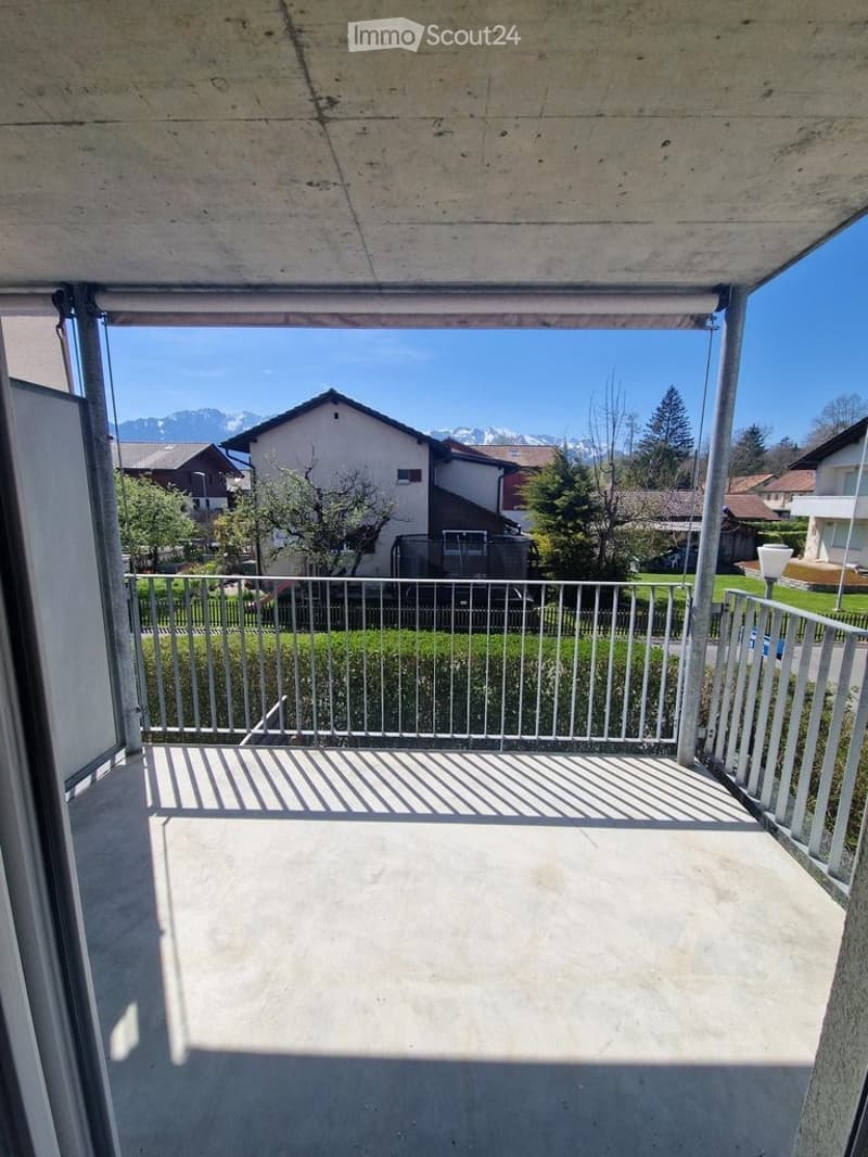 Balcony with metal railing, concrete floor, and scenic mountain view in the background.