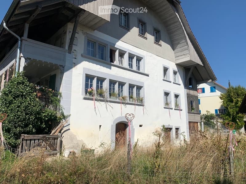 Two-story white house with multiple windows, balcony, and decorative elements.