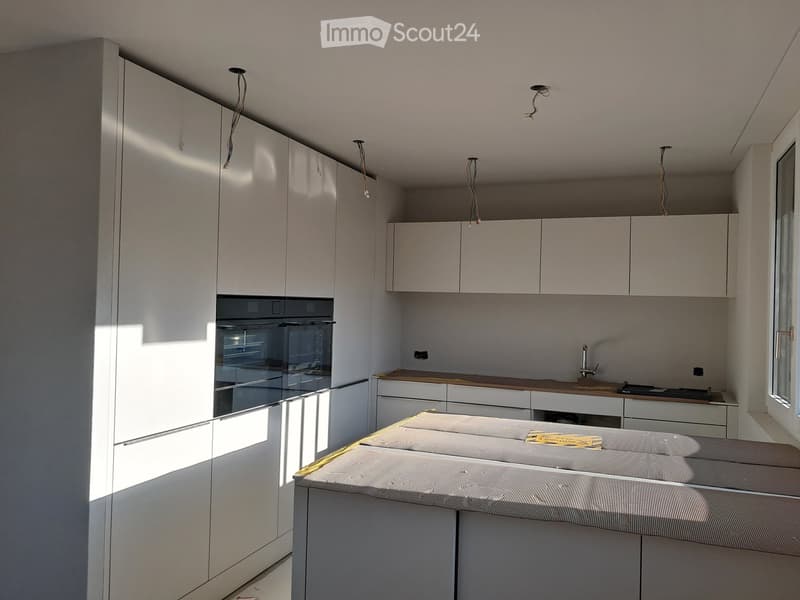 Modern kitchen with white cabinets, a built-in oven, a sink with a faucet, and a central island with a wooden countertop.