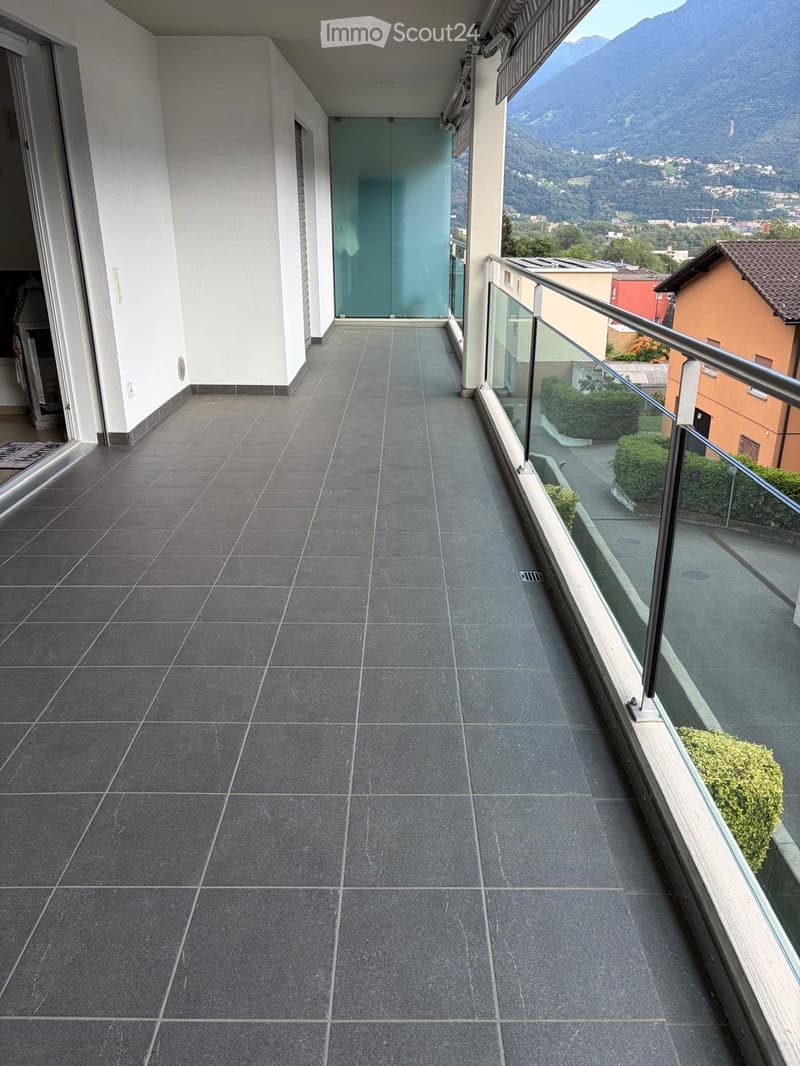 Balcony with dark grey tiled floor, glass railing, and scenic mountain view.
