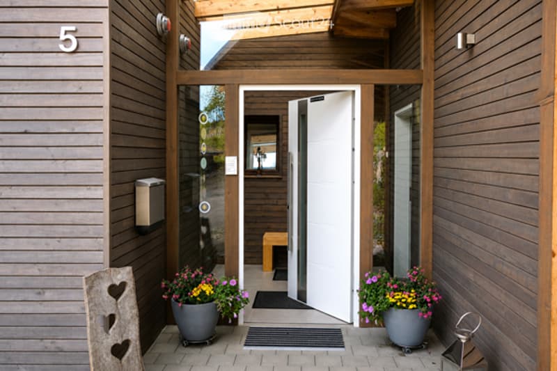 Entrance hallway with wooden walls, potted plants, and a small bench visible inside the doorway.
