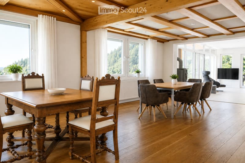 Dining room with wooden table and chairs, a bowl on the table, and a TV in the background.