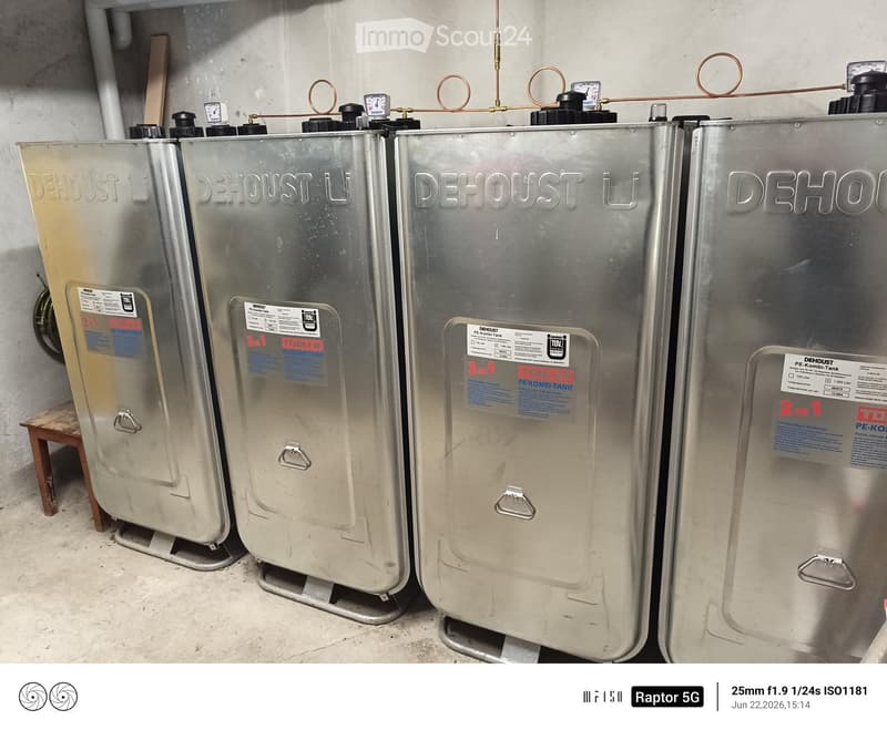 Four large silver water tanks labeled "DEHOUST" are lined up against a concrete wall, each equipped with gauges and handles.