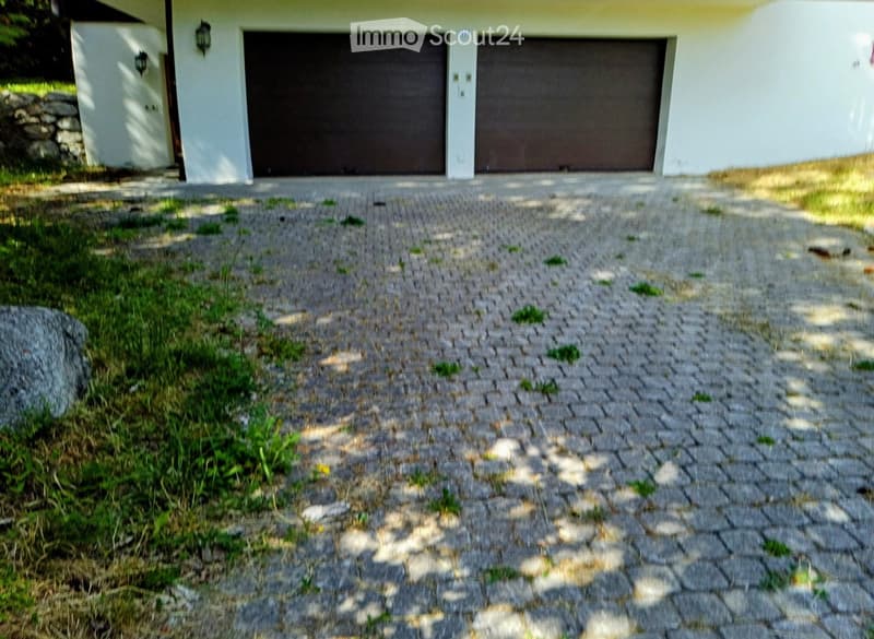 A modern house with a light-colored exterior, two garage doors, and a paved driveway.