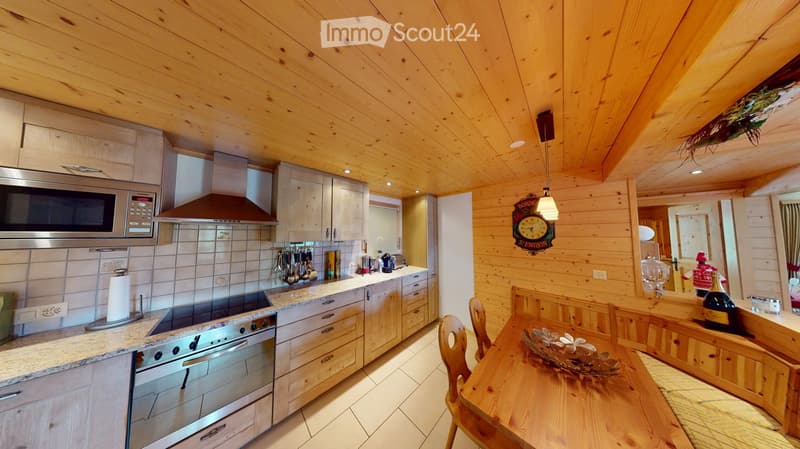 Cozy kitchen with wooden walls and ceiling, granite countertops, stainless steel appliances, and a dining area with a wooden table and chairs.