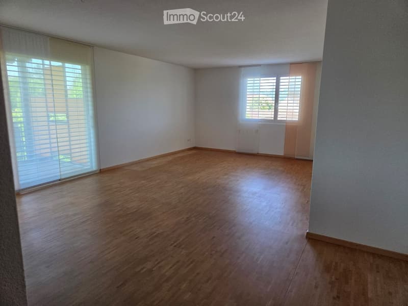 Empty room with wooden flooring, white walls, and large windows with blinds. No furniture or equipment present.