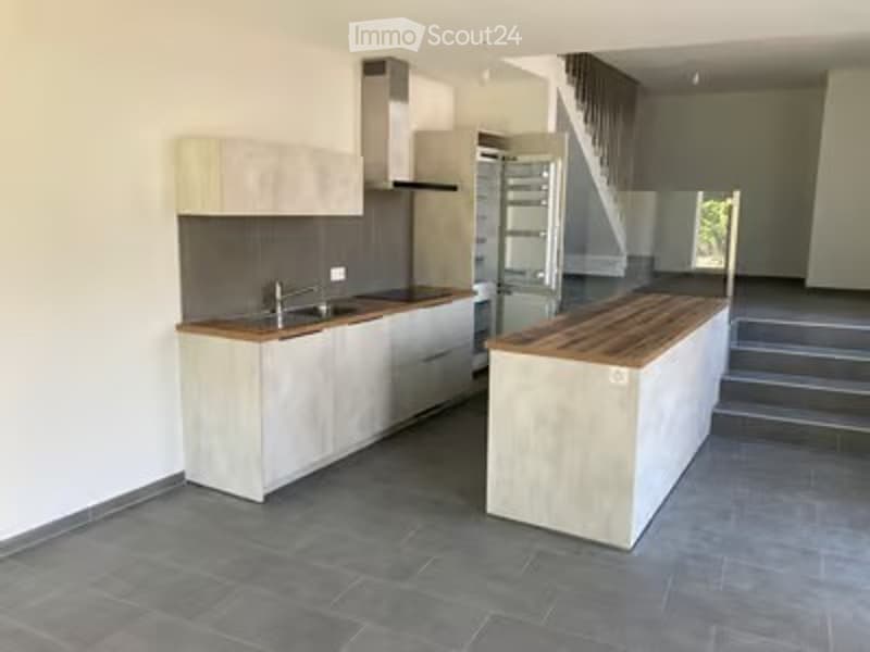 Modern kitchen with light-colored cabinets, a central island, and a sink area. The space is clean and well-lit, with a contemporary design.