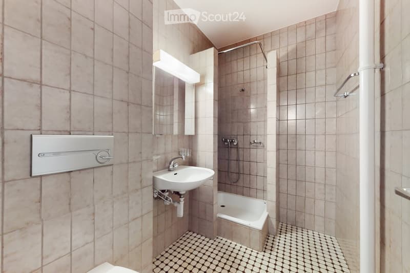 Bathroom with beige tiled walls and floor, a white sink, a bathtub, a mirror, and a showerhead.