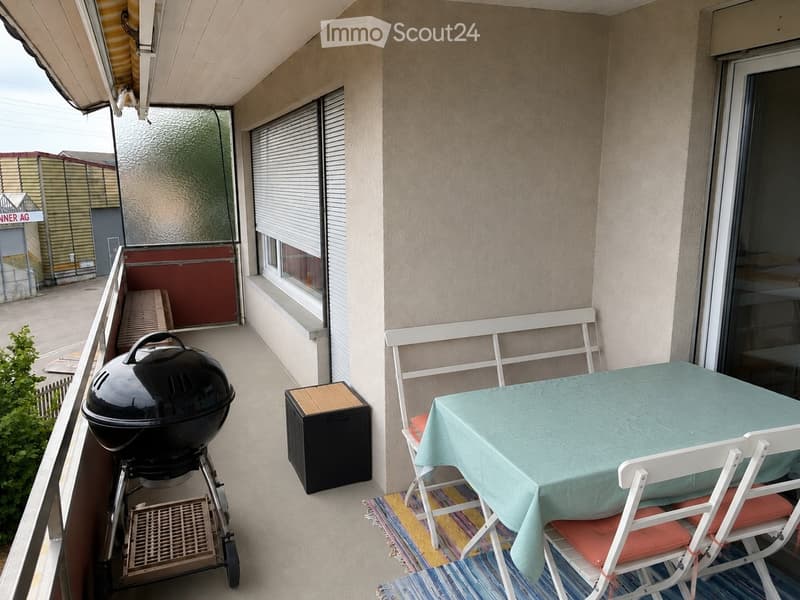 Balcony with a table, chairs, barbecue, and storage box.