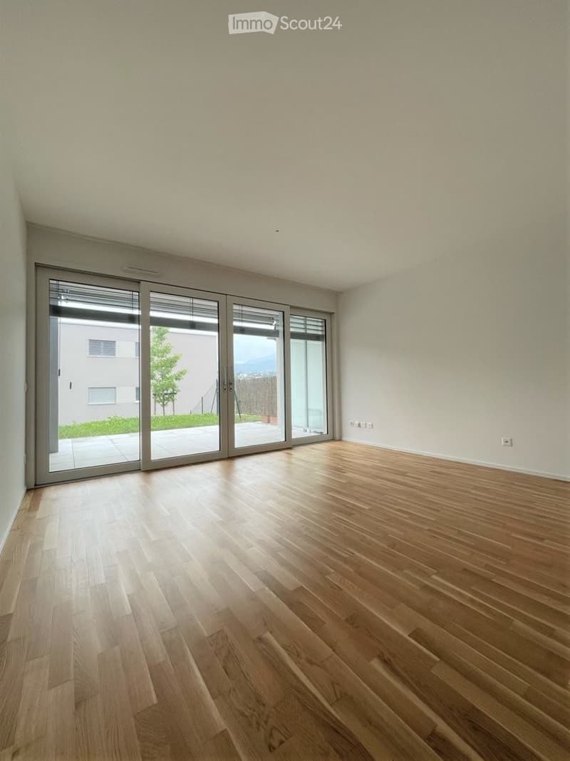 Empty room with light wooden flooring and large sliding glass doors leading to an outdoor area.
