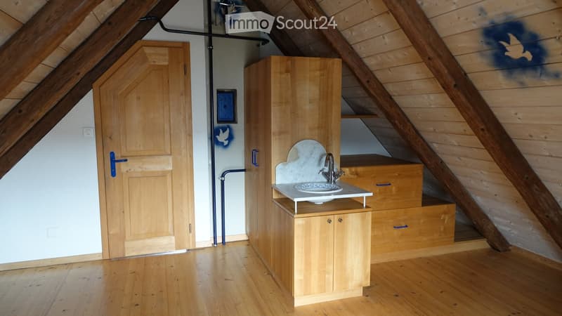Empty attic room with wooden walls, floor, and a small sink unit. No furniture or equipment present.